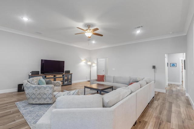 living area featuring light wood-style floors, baseboards, and crown molding