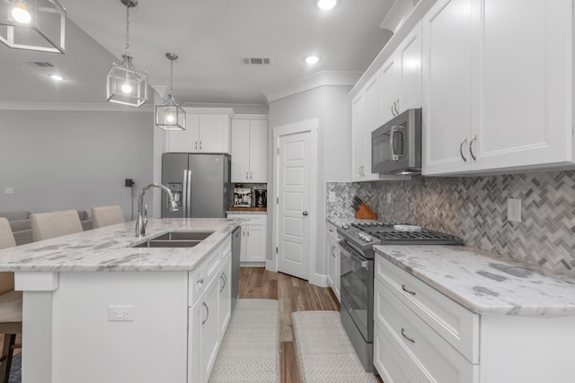 kitchen with stainless steel appliances, a sink, white cabinets, an island with sink, and a kitchen bar