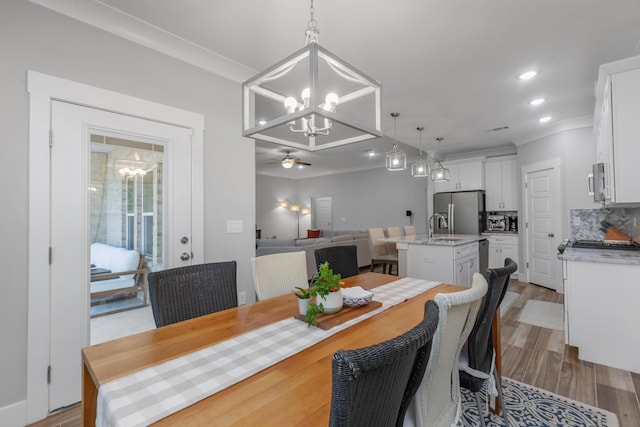 dining space featuring ceiling fan with notable chandelier, ornamental molding, light wood-type flooring, and recessed lighting