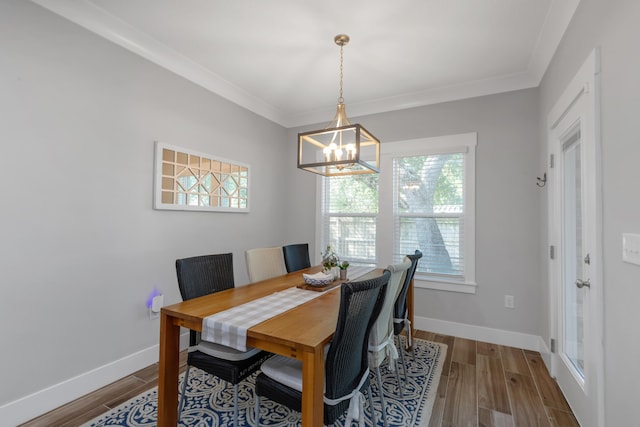 dining space with an inviting chandelier, crown molding, baseboards, and wood finished floors