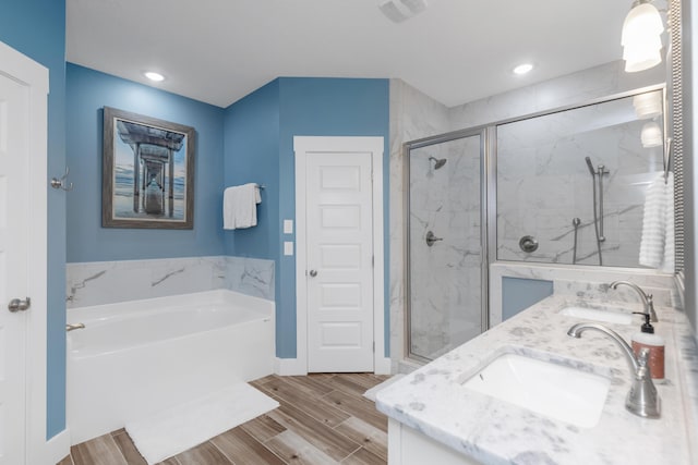 full bath with a garden tub, a sink, and wood finish floors