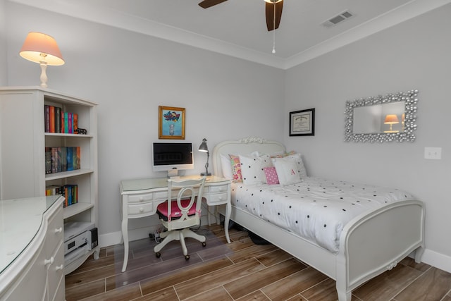 bedroom featuring wood finish floors, a ceiling fan, visible vents, baseboards, and ornamental molding