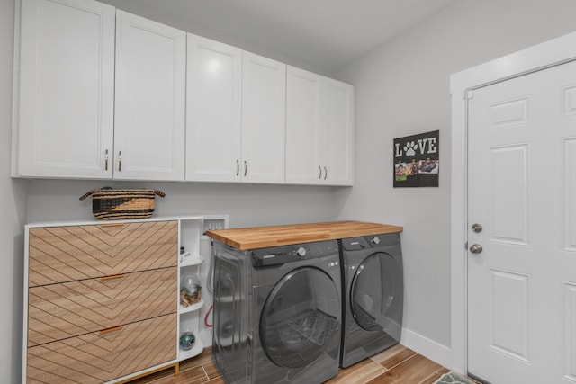 laundry area with cabinet space, baseboards, light wood finished floors, and independent washer and dryer