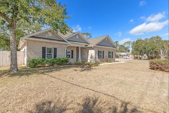 view of front of house with a front yard, brick siding, and fence