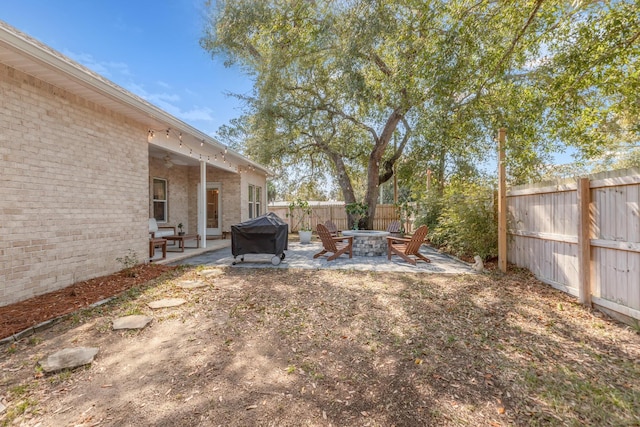 view of yard featuring a fire pit, a patio, and a fenced backyard