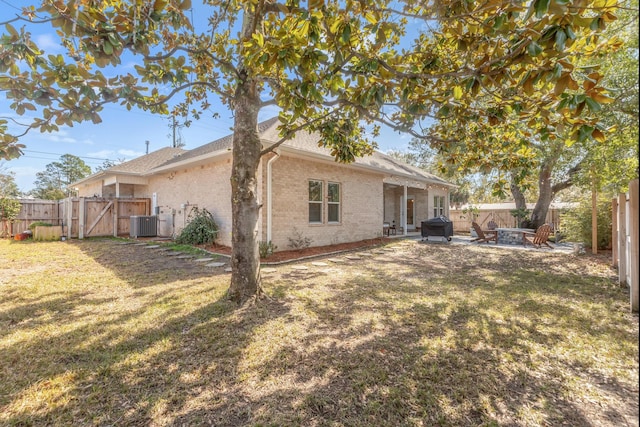 back of house featuring central AC unit, a lawn, a fenced backyard, a gate, and brick siding