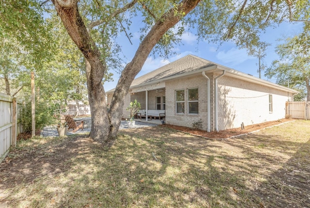 rear view of property featuring a patio area, a fenced backyard, brick siding, and a lawn