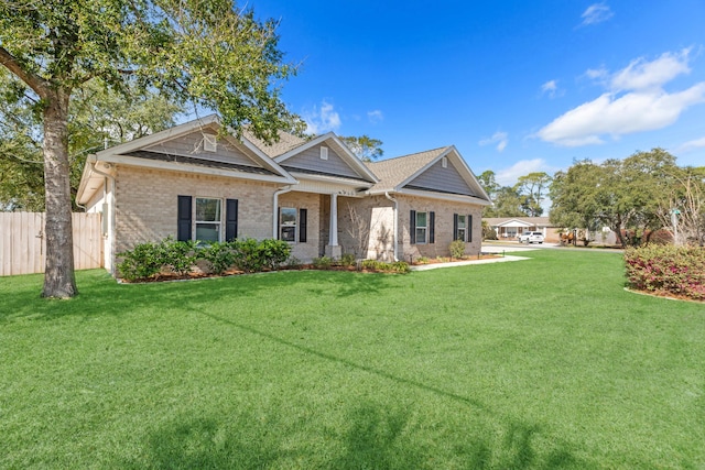 view of front of house with a front lawn, fence, and brick siding