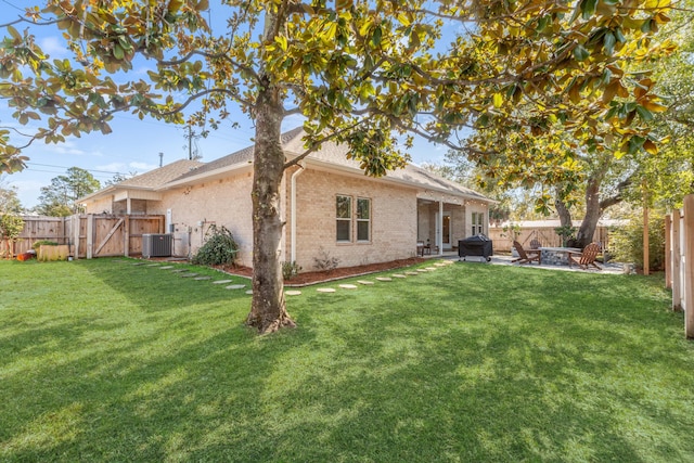 back of property featuring a gate, a fenced backyard, brick siding, and a lawn