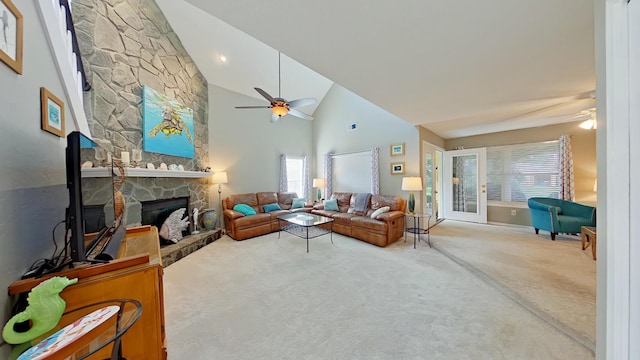 living room with ceiling fan, a stone fireplace, and high vaulted ceiling