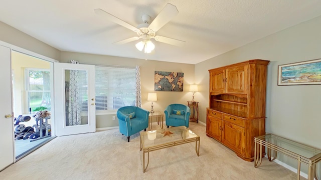 living area with light colored carpet, french doors, and ceiling fan