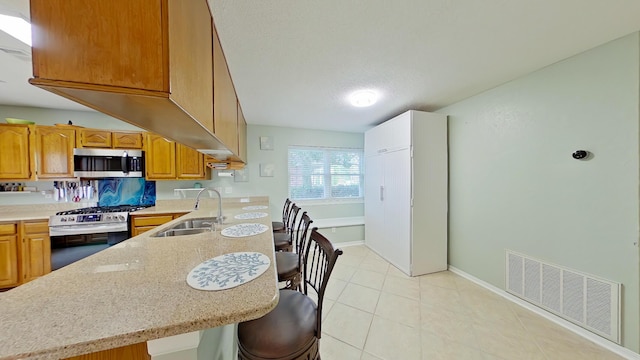 kitchen featuring sink, stainless steel appliances, a kitchen breakfast bar, a textured ceiling, and kitchen peninsula