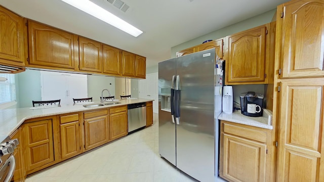 kitchen with appliances with stainless steel finishes, sink, and light tile patterned floors