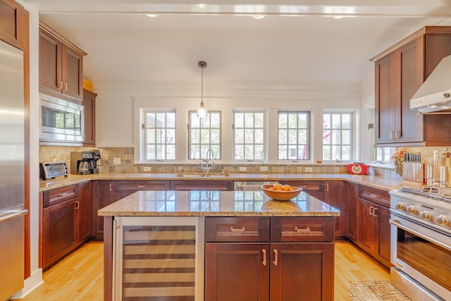 kitchen with wine cooler, sink, a center island, appliances with stainless steel finishes, and pendant lighting