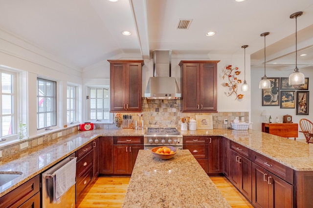 kitchen featuring decorative light fixtures, wall chimney exhaust hood, stainless steel appliances, light stone countertops, and light hardwood / wood-style flooring