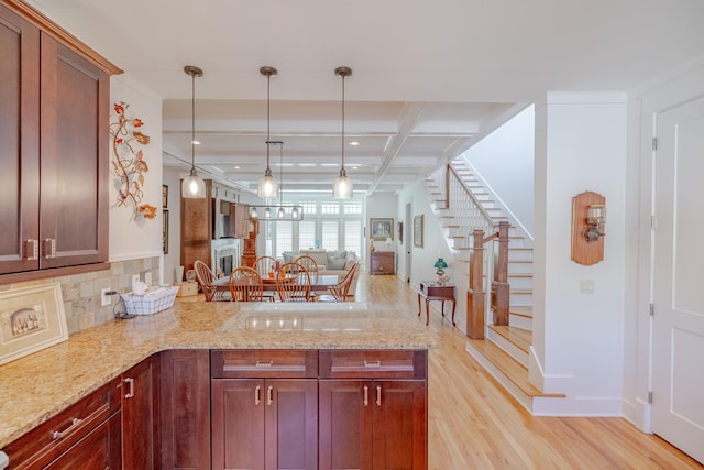 kitchen featuring light stone countertops, coffered ceiling, light hardwood / wood-style flooring, and kitchen peninsula