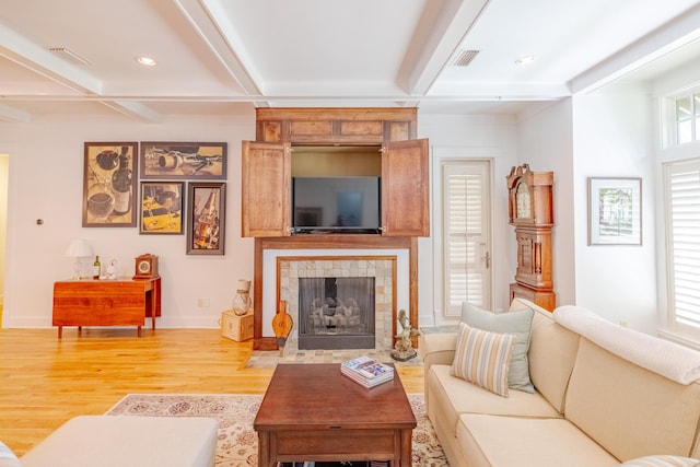 living room with beam ceiling, a tile fireplace, coffered ceiling, and light hardwood / wood-style floors