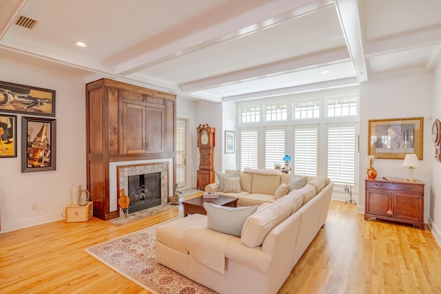 living room featuring a fireplace, light hardwood / wood-style floors, and beamed ceiling