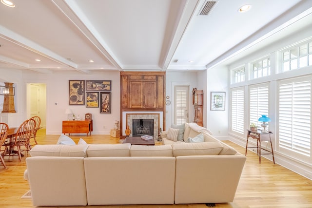 living room featuring a fireplace, beam ceiling, and light wood-type flooring