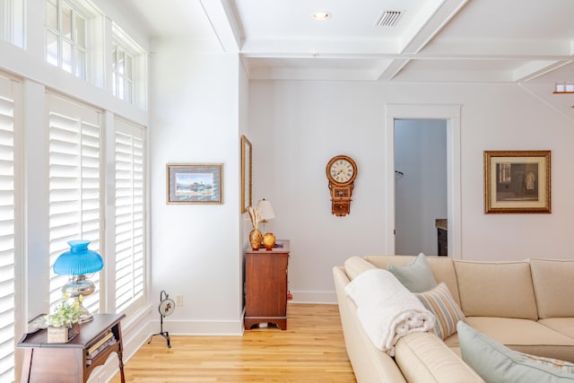 living room featuring coffered ceiling, a wealth of natural light, beam ceiling, and light hardwood / wood-style floors