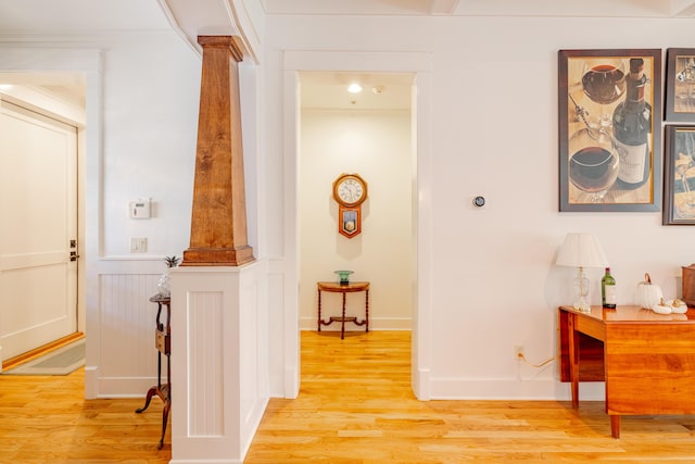 hallway featuring decorative columns and light wood-type flooring