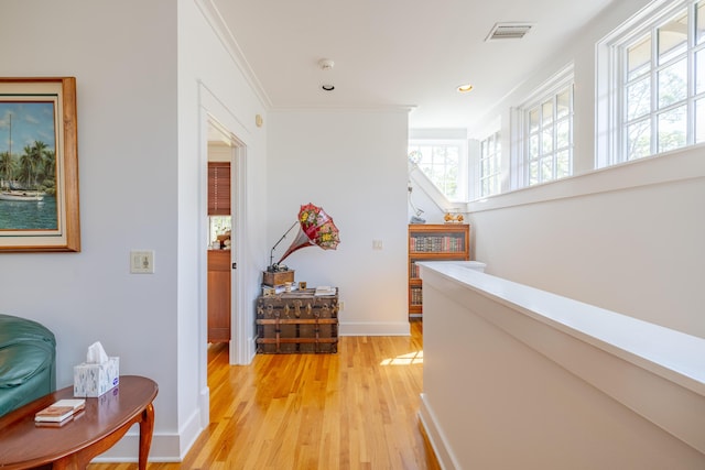 hall with crown molding and light hardwood / wood-style flooring