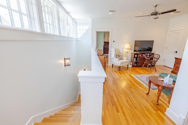 staircase with ceiling fan and hardwood / wood-style floors