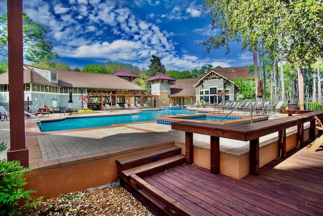 view of swimming pool with a wooden deck, a community hot tub, and a patio area