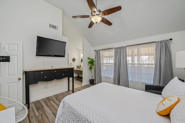 bedroom with vaulted ceiling, wood finished floors, visible vents, and baseboards