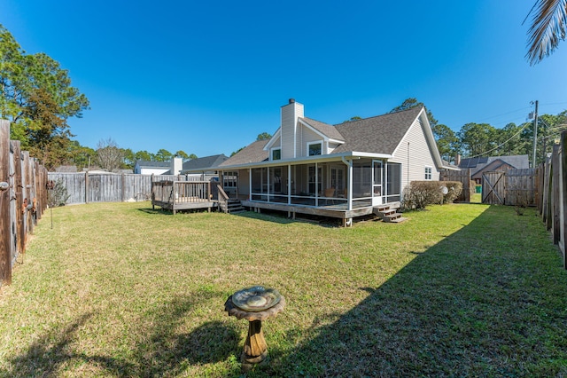 back of house featuring a sunroom, a fenced backyard, a chimney, and a yard