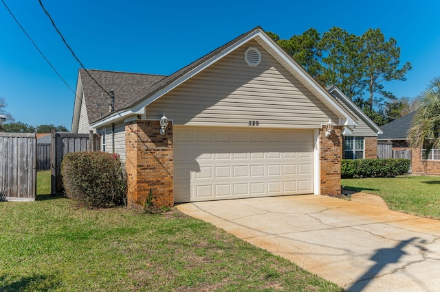 view of property exterior with a garage, concrete driveway, fence, a yard, and brick siding