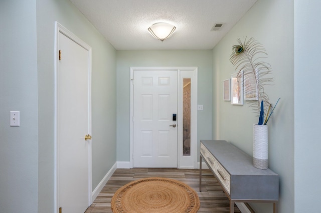 interior space with baseboards, a textured ceiling, visible vents, and wood finished floors