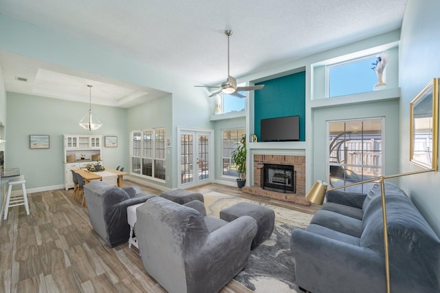 living area featuring a towering ceiling, plenty of natural light, a fireplace, and wood finished floors