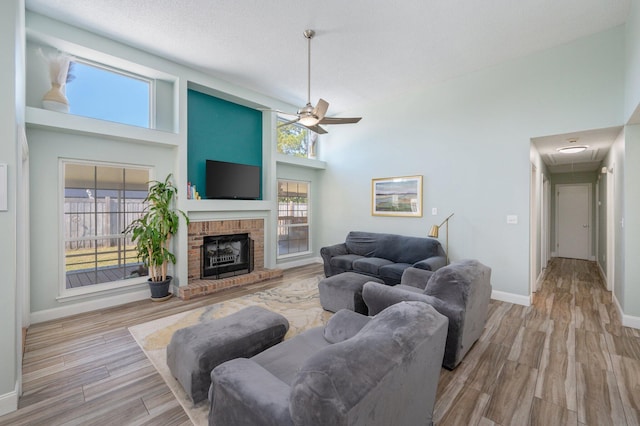 living room with a high ceiling, light wood-type flooring, a fireplace, and baseboards