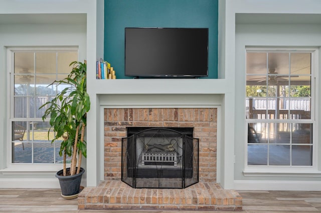 room details featuring ceiling fan, a fireplace, and wood finished floors