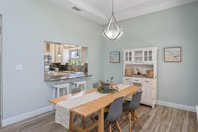 dining room with visible vents, light wood finished floors, and baseboards