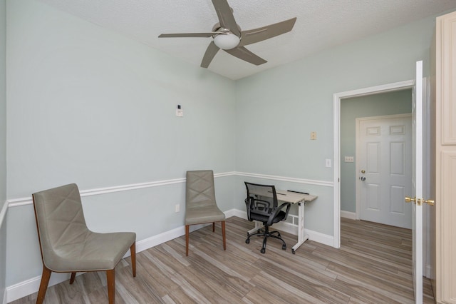 office space featuring baseboards, ceiling fan, a textured ceiling, and light wood-style floors