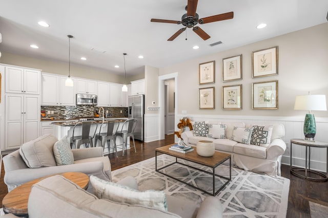 living room with dark wood-type flooring and ceiling fan