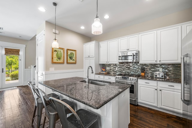 kitchen with sink, white cabinetry, appliances with stainless steel finishes, pendant lighting, and a kitchen island with sink