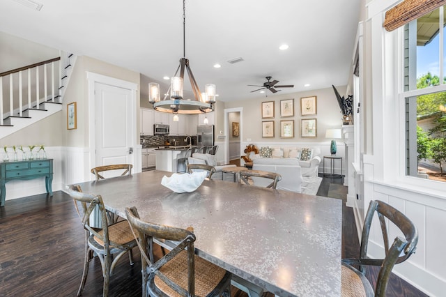 dining area with dark hardwood / wood-style floors and ceiling fan with notable chandelier