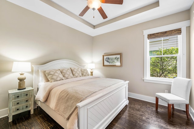 bedroom with a tray ceiling, dark hardwood / wood-style floors, and ceiling fan