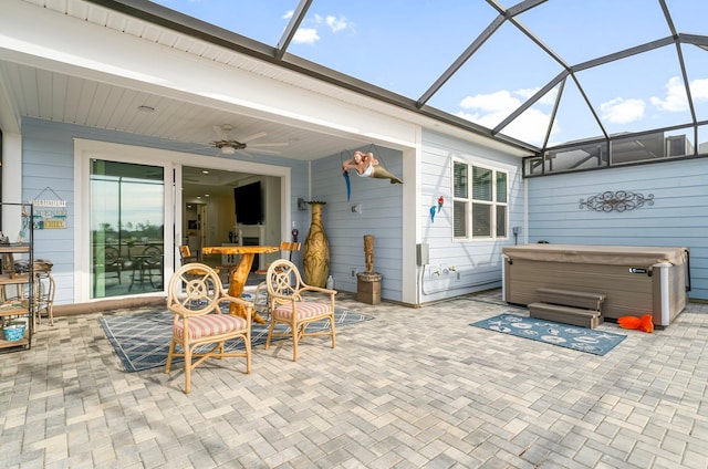 view of patio with a lanai, a hot tub, and ceiling fan