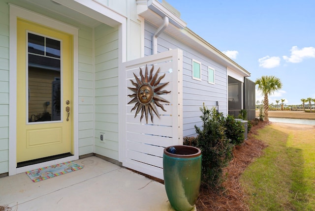 view of exterior entry with central AC unit and a lawn