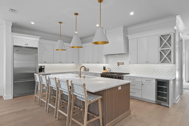 kitchen featuring wine cooler, white cabinetry, stainless steel built in refrigerator, and premium range hood