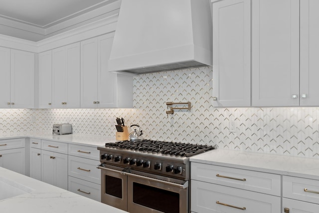 kitchen with white cabinetry, premium range hood, and double oven range