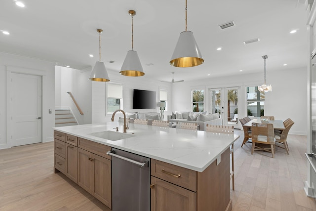 kitchen with decorative light fixtures, dishwasher, sink, and a center island with sink