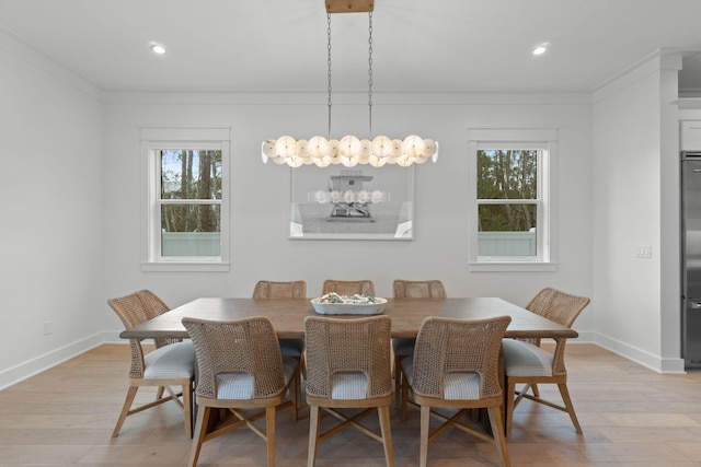 dining room with ornamental molding and light hardwood / wood-style flooring