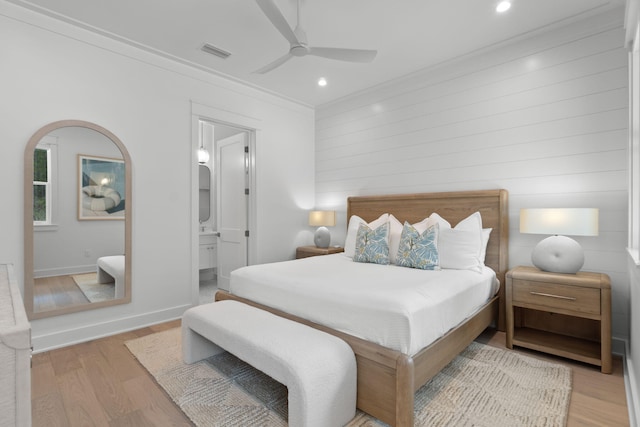 bedroom with crown molding, connected bathroom, ceiling fan, and light hardwood / wood-style flooring