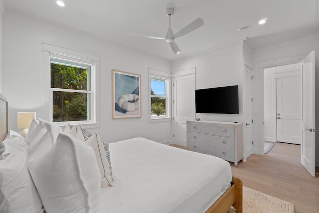 bedroom with crown molding, multiple windows, and light hardwood / wood-style flooring