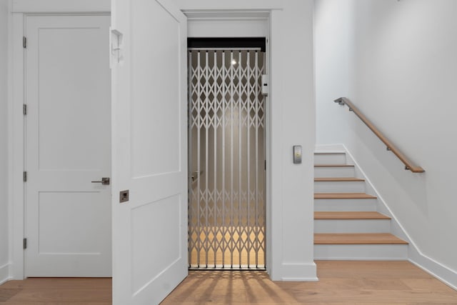 stairs featuring hardwood / wood-style floors and elevator